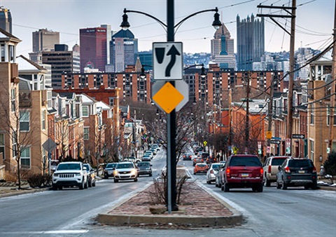 City street with center median island running down Pittsburgh street with city in the background.
