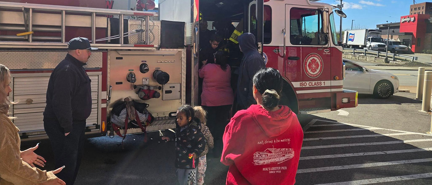 Firefighters showing the inside of a fire engine to children.