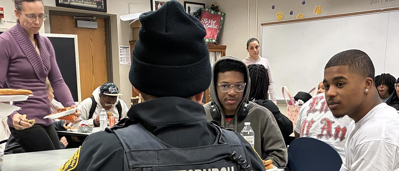 Two teen boys sitting at table with Officer.