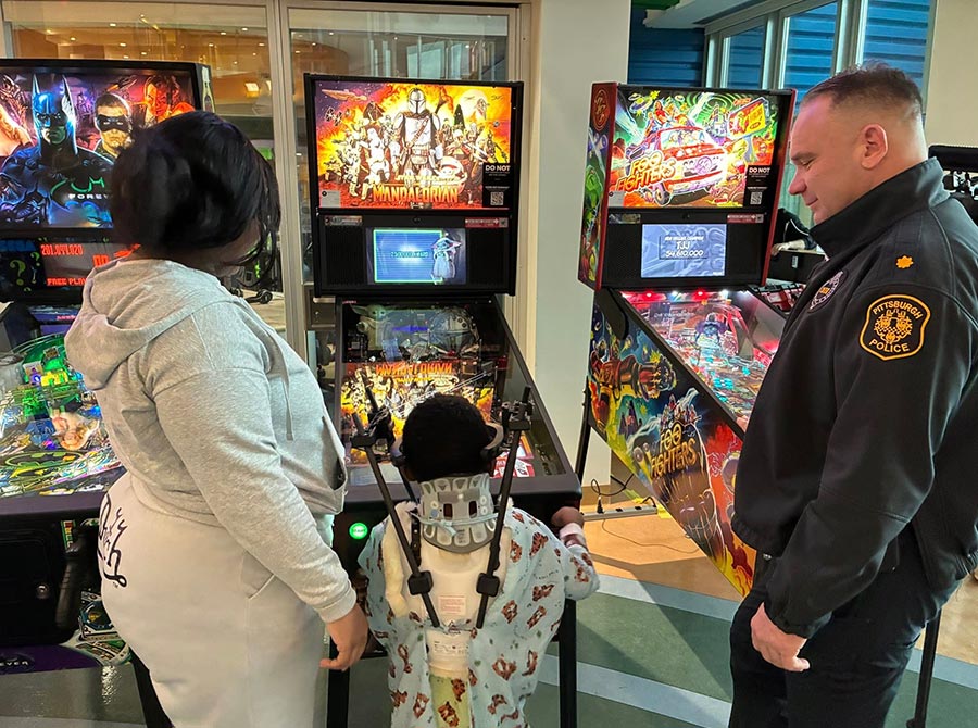 Officer, mother and child enjoying a game of pinball.