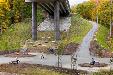 Photo of people interacting with public art under the Fern Hollow Bridge