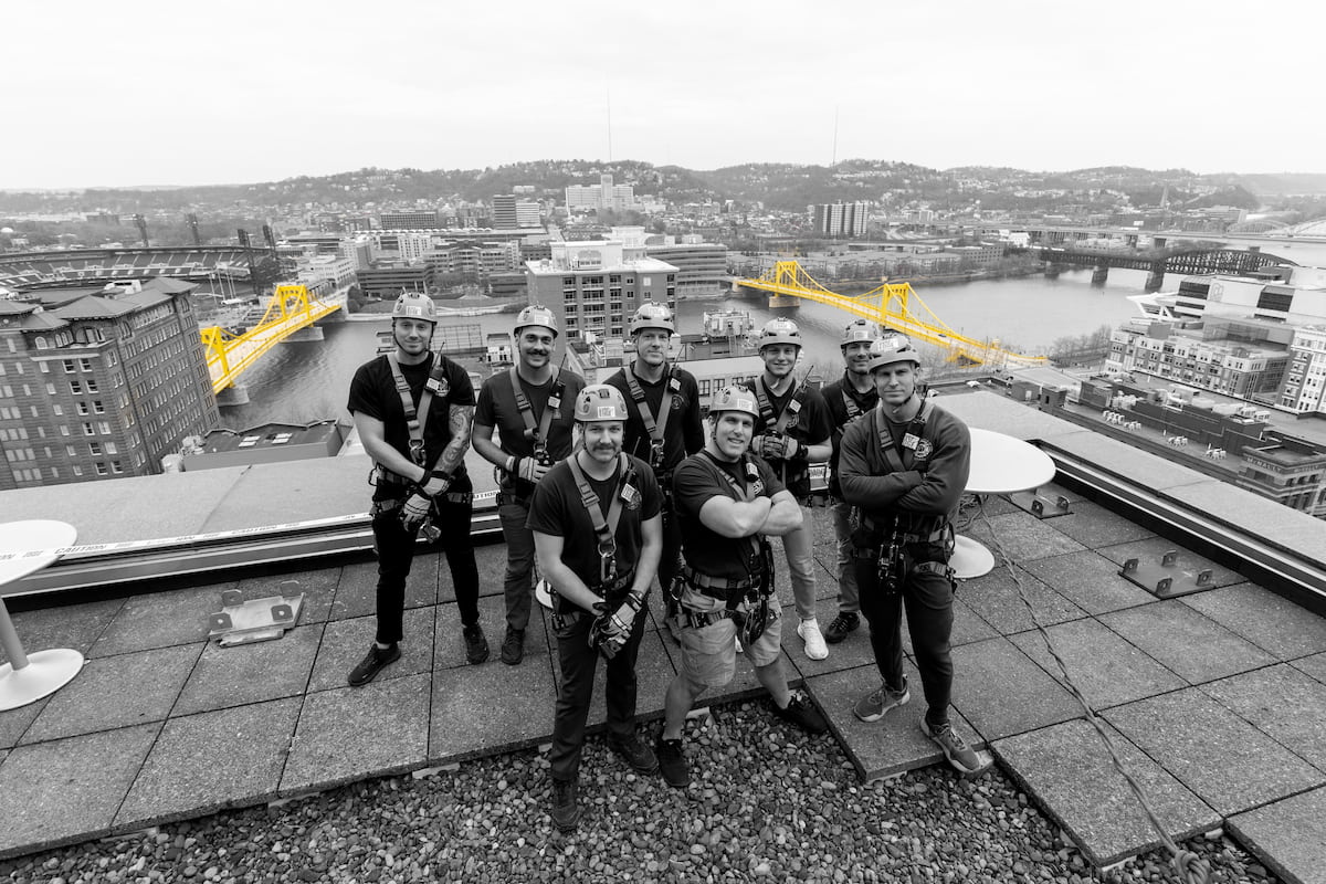 Fire crew on top of building with bridges in background.