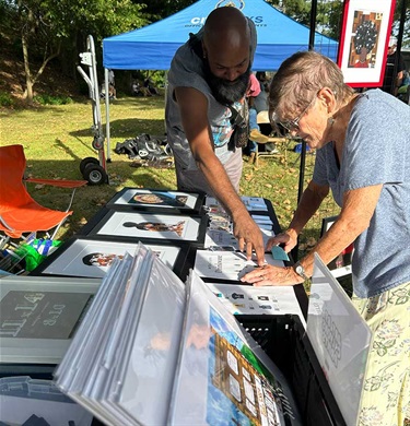 Man and woman looking through art for sale at booth.