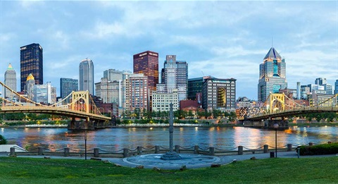 City of Pittsburgh - Day time wide angle shot near river with two bridges and buildings in the background.